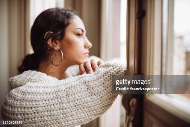 pensive woman in front of the window - tristeza imagens e fotografias de stock
