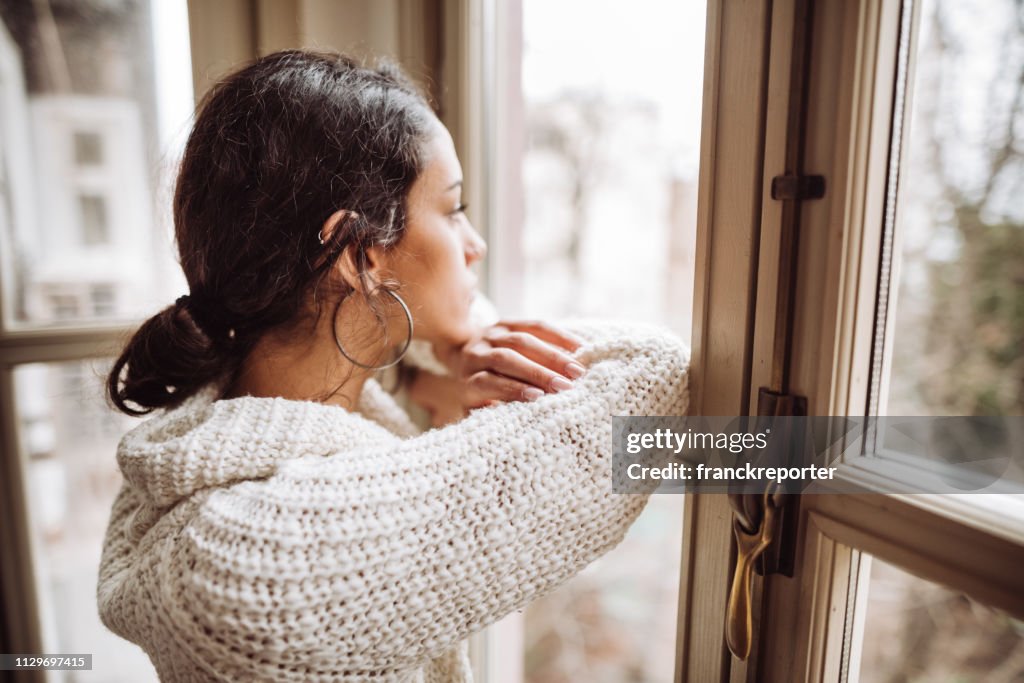 Mujer pensativa frente a la ventana