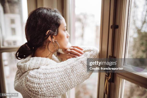 pensive woman in front of the window - broken heart stock pictures, royalty-free photos & images