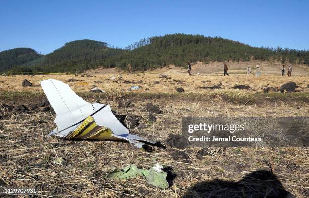 Piece of the fuselage of ET Flight 302 can be seen in the foreground as local residents collect debris at the scene where Ethiopian Airlines Flight...