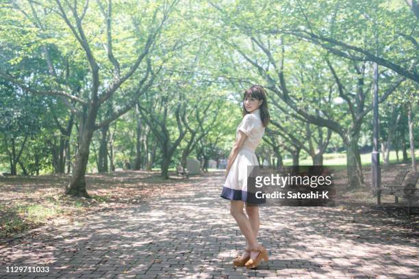 公共の公園で肩越しに見ている若い女性 - 美大生　日本 ストックフォトと画像