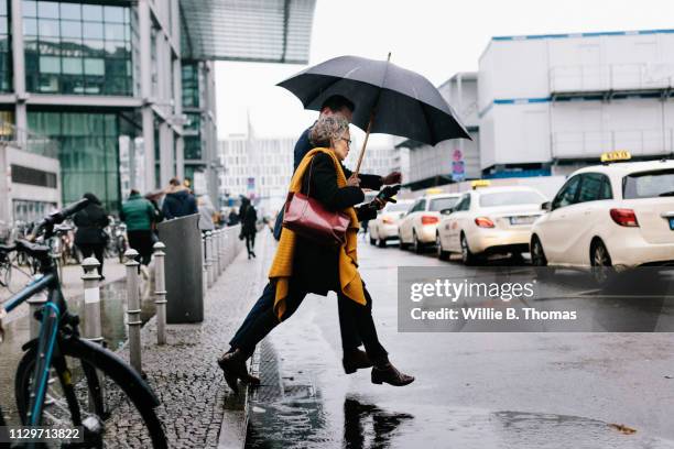 business associates running for cab in rain - carro de corrida fotografías e imágenes de stock