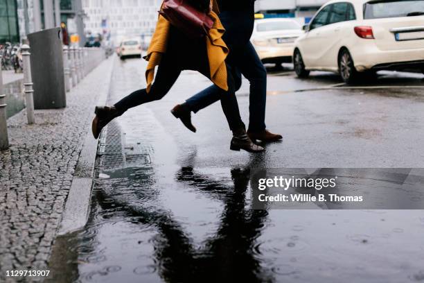 close-up of two people jumping over puddle - puddle ストックフォトと画像