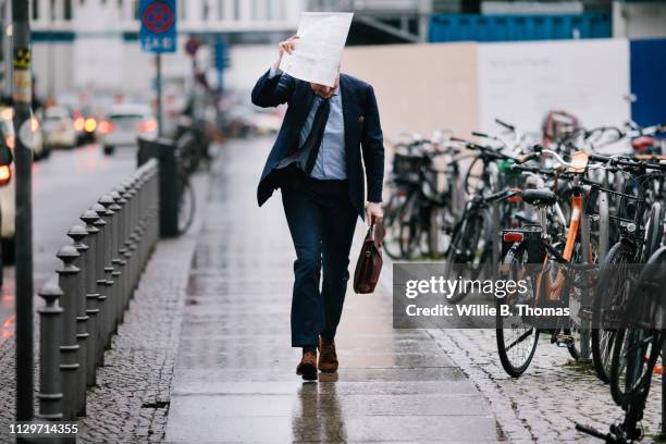 businessman covering up in the rain - rain stock-fotos und bilder