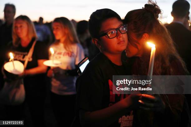 Carol Ortez hugs her son, Aaron Ortez, as he holds a candle during a memorial service at Pine Trails Park for the victims of the mass shooting at...