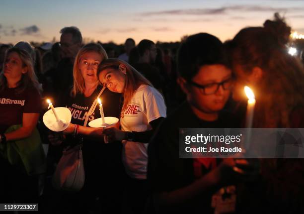 Lynda Miller and Soona Buchanan hold their candles during a memorial service at Pine Trails Park for the victims of the mass shooting at Marjory...