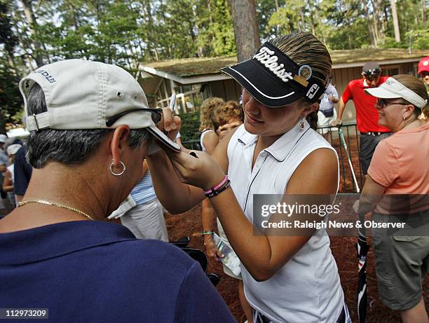 Alexis Thompson right, autographs fan Laura Trippy's hat, after she finished her round of the second round of the U.S. Women's Open at Pine Needles...