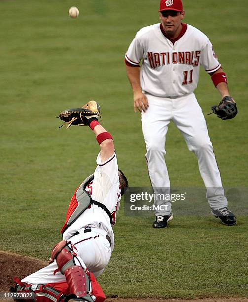 Washington Nationals catcher Brian Schneider makes a catch in front of Ryan Zimmerman on a ball hit by Milwaukee Brewers Ryan Braun in the 2nd inning...