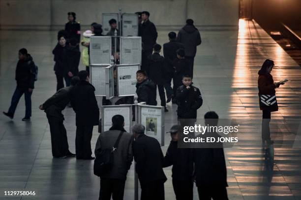 General view shows commuters reading the Rodong Sinmun newspaper at a news stand at a subway station in Pyongyang on March 11, 2019. - North Koreans...