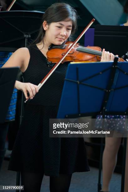blandat-etniska tonåriga flicka på scenen spelar violin konsert - klassisk orkestermusik bildbanksfoton och bilder