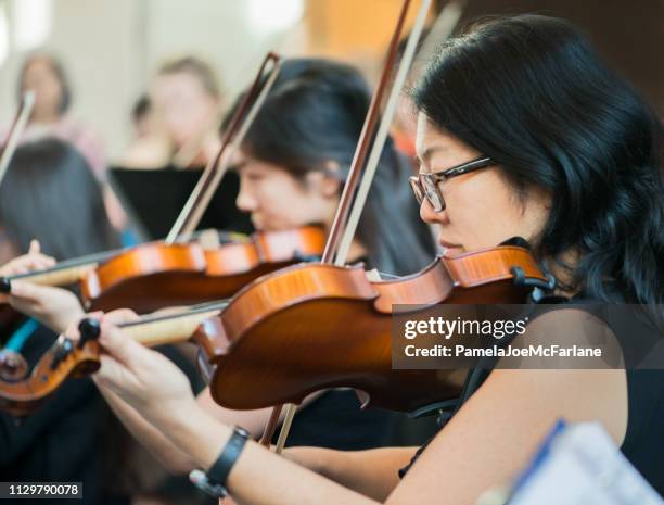 sezione violino dell'orchestra comunitaria di tutte le età che si esibisce in concerto - daughter band foto e immagini stock