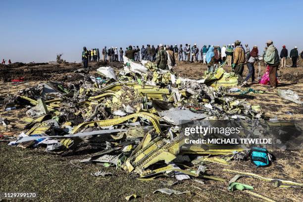 People stand near collected debris at the crash site of Ethiopia Airlines near Bishoftu, a town some 60 kilometres southeast of Addis Ababa,...