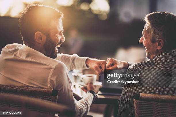 heureux hommes d’affaires donnant l’autre poing bosse dans le café de rue au coucher du soleil. - fist bump photos et images de collection