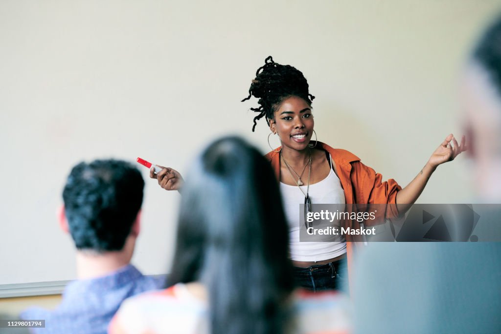 Portrait of confident teacher gesturing while teaching students in language class