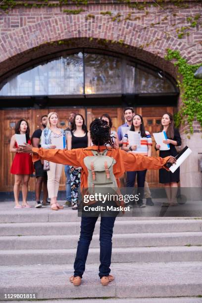 conductor directing choir outside language school - koor stockfoto's en -beelden