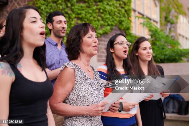 multi-ethnic choir singers performing outside language school - koor stockfoto's en -beelden