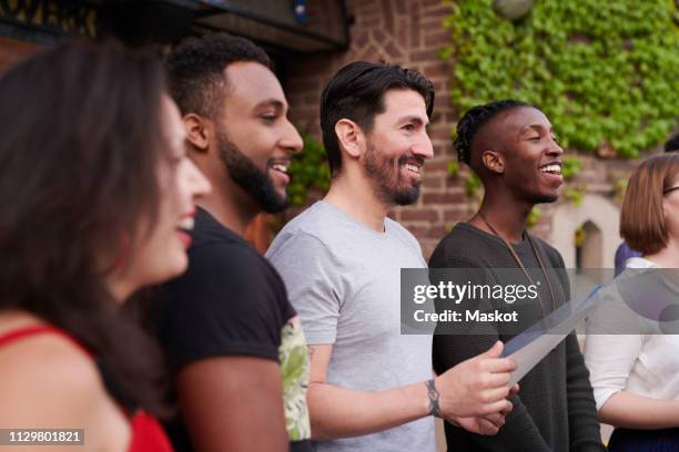 choir singers with music sheet singing outside language school - chorproben stock-fotos und bilder