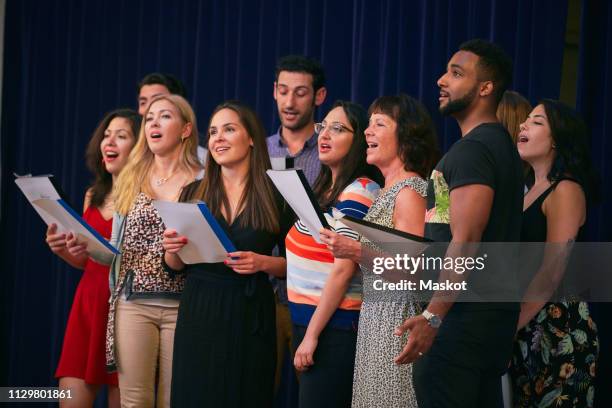 male and female friends holding music sheets rehearsing on stage - chorsänger stock-fotos und bilder