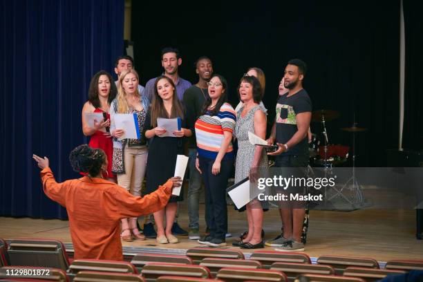 teacher directing choir on stage in language school - choir stage stock pictures, royalty-free photos & images