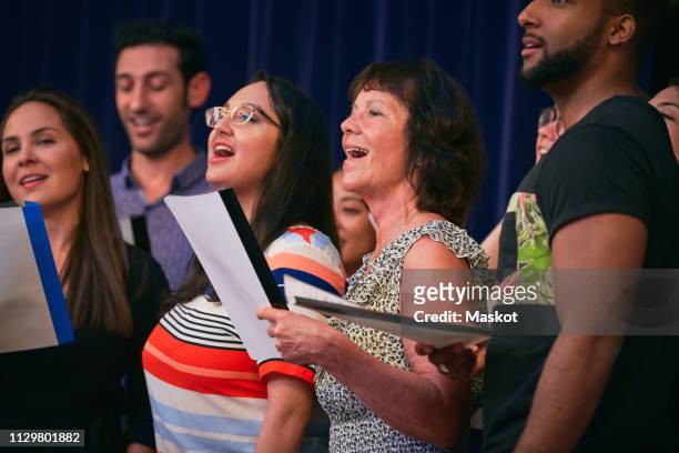 multi-ethnic choir singers performing on stage in auditorium - choir stage stock pictures, royalty-free photos & images