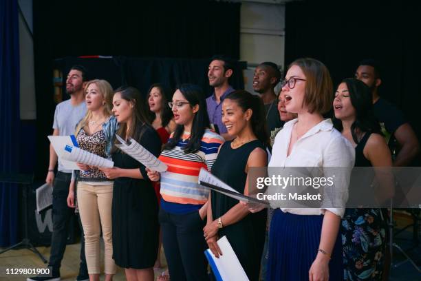 multi-ethnic male and female students singing in choir at auditorium - choir stage stock pictures, royalty-free photos & images