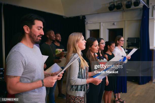 male and female friends with music sheets singing at choir practice - choir stage stock pictures, royalty-free photos & images