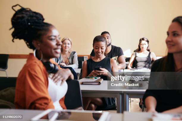 mature woman using smart phone while sitting with classmates in language class - student visa stockfoto's en -beelden