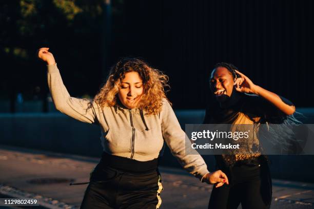 excited friends dancing at skateboard park during sunset - adolescenti ballano foto e immagini stock