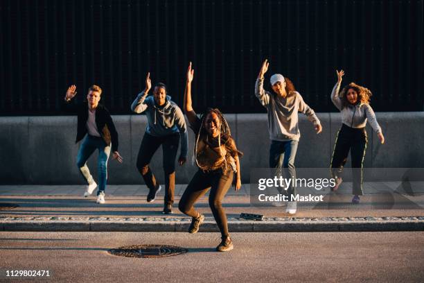 full length of multi-ethnic friends dancing on sidewalk in city - hip hop dance fotografías e imágenes de stock