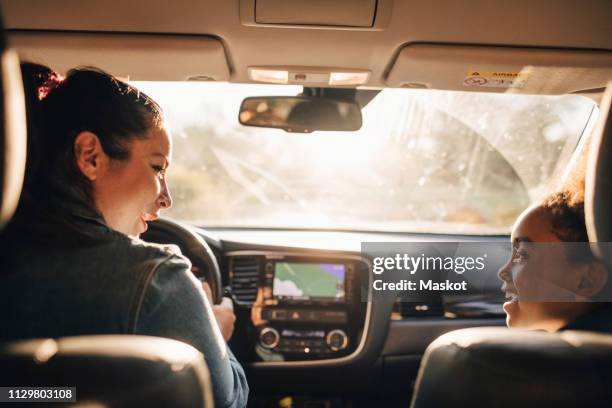 smiling woman with daughter sitting in electric car during picnic - girl driving imagens e fotografias de stock