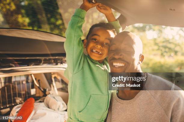 portrait of smiling boy with father at picnic spot in park - parklücke stock-fotos und bilder