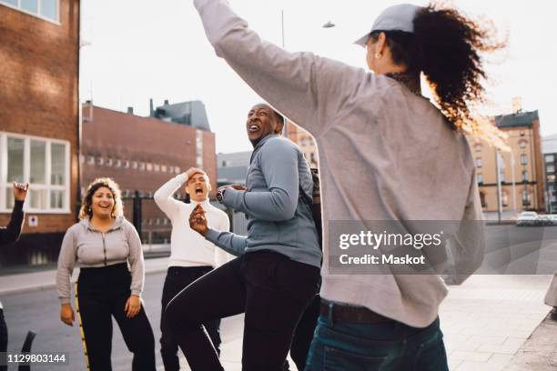 multi-ethnic cheerful friends dancing on street in city - stockholm city stock-fotos und bilder