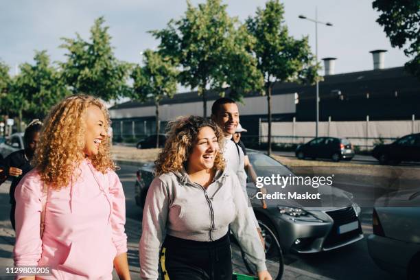 cheerful friends walking on street by cars in city - guy girl street laugh stock pictures, royalty-free photos & images