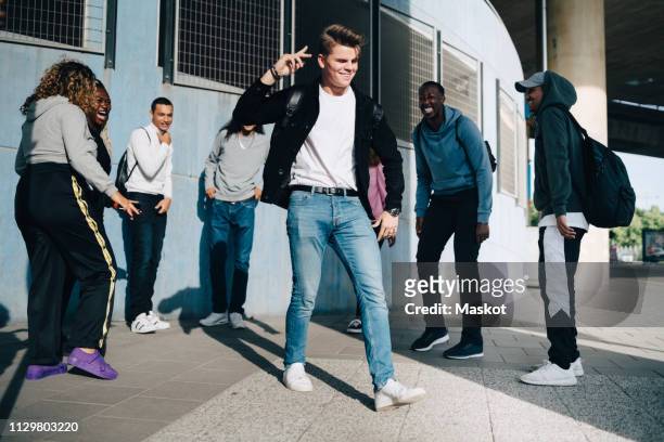 cheerful friends looking at young man standing on sidewalk in city - mann ganzkörper lachen stehen stock-fotos und bilder