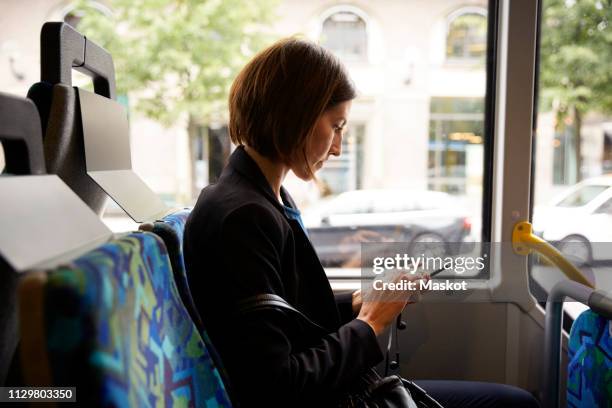 side view of businesswoman using smart phone while sitting in bus - bus side view stock pictures, royalty-free photos & images