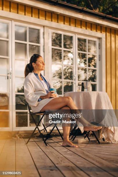 thoughtful mature woman drinking coffee while sitting at patio in holiday villa - coffee on patio stock pictures, royalty-free photos & images
