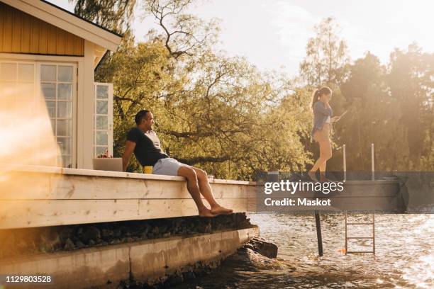 mature man looking at woman using digital tablet while sitting on patio by lake - tablet paar sommer stock-fotos und bilder