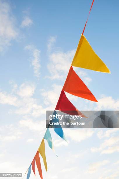 colorful bunting flags/ pennant chain for party decoration against sky - pennant stock-fotos und bilder