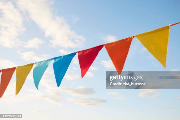 colorful bunting flags/ pennant chain for party decoration against sky - bandierine foto e immagini stock