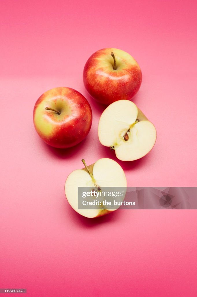 High angle view of halved apples on pink background