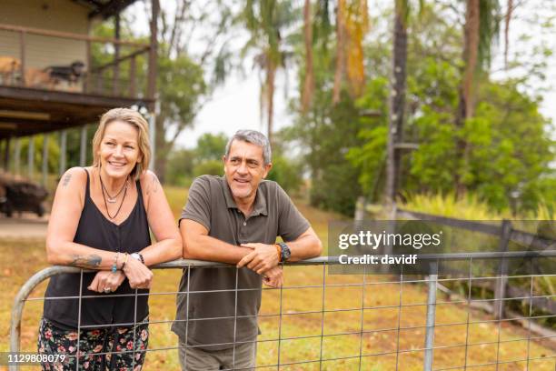 happy mature couple talking together at their farm - house fence stock pictures, royalty-free photos & images