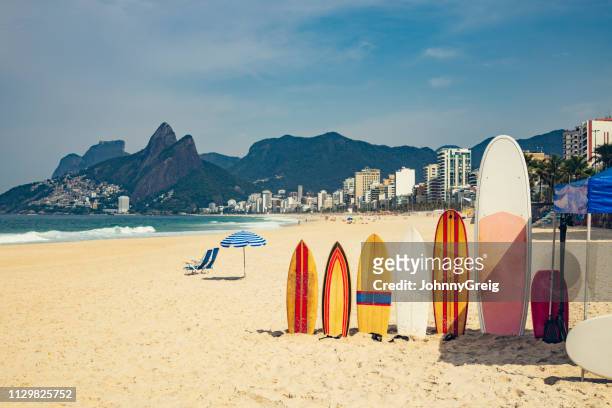 strand von ipanema mit surfbrettern und sonnenschirm - rio de janeiro stock-fotos und bilder