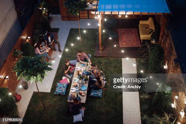 vue de dessus d'un amis multi-ethniques appréciant la partie de dîner à la cour - garden night photos et images de collection