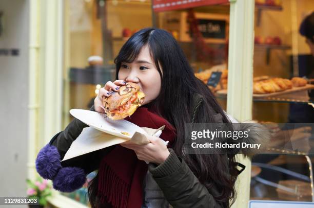 a young woman eating street food - adult eating no face stock pictures, royalty-free photos & images