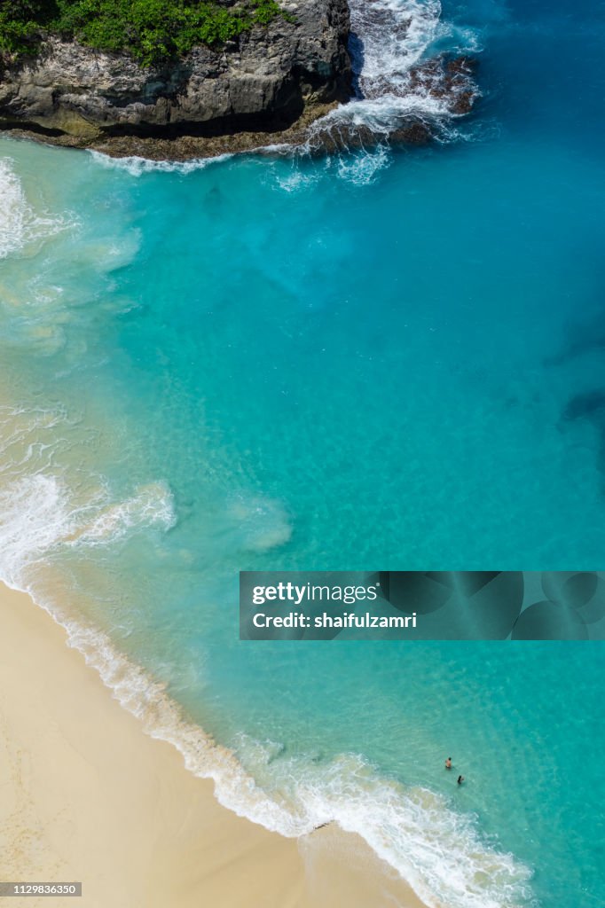 Vertiginous, swirling foamy water waves at the ocean photographed from above cliff.