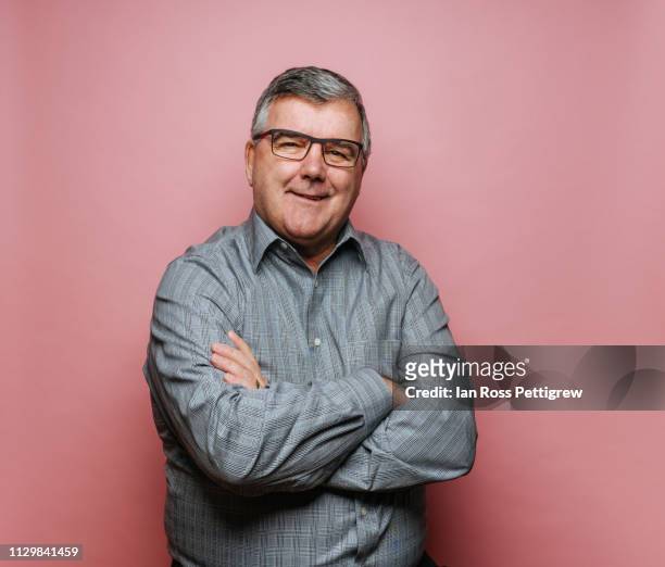 middle-aged man with glasses on pink background - männer über 40 stock-fotos und bilder