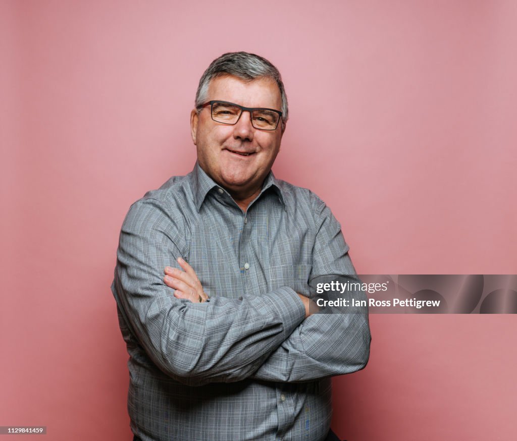 Middle-aged man with glasses on pink background