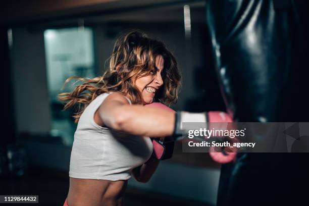 frau boxer stanzen einen boxsack - female boxer stock-fotos und bilder