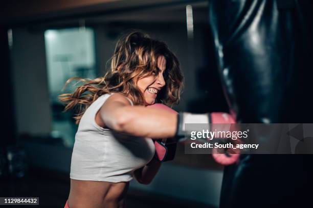 boxer femme poinçonnant un punching-bag - irréductibilité photos et images de collection