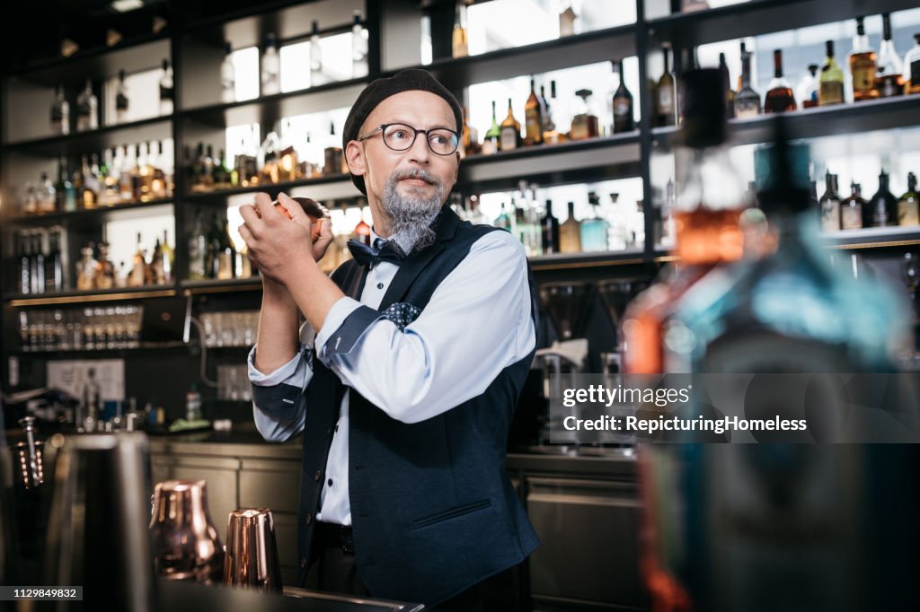 A sophisticated bartender looks aside while making drinks.